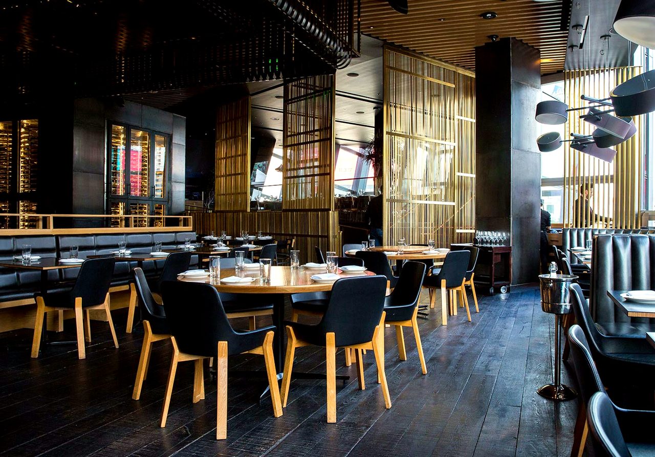 A dining room with long tables, timber chairs and low pendant lamps