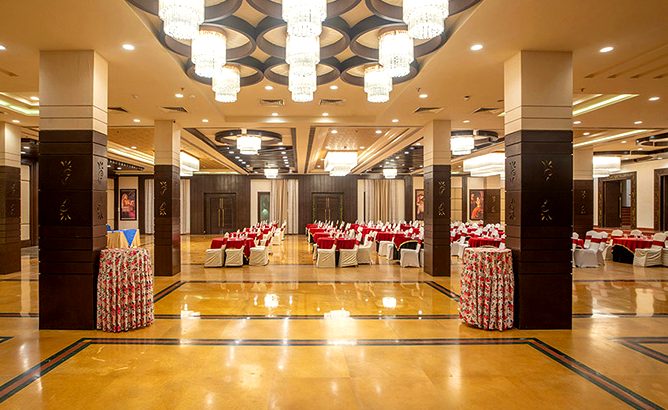 A long function room set with round tables under a bright ceiling
